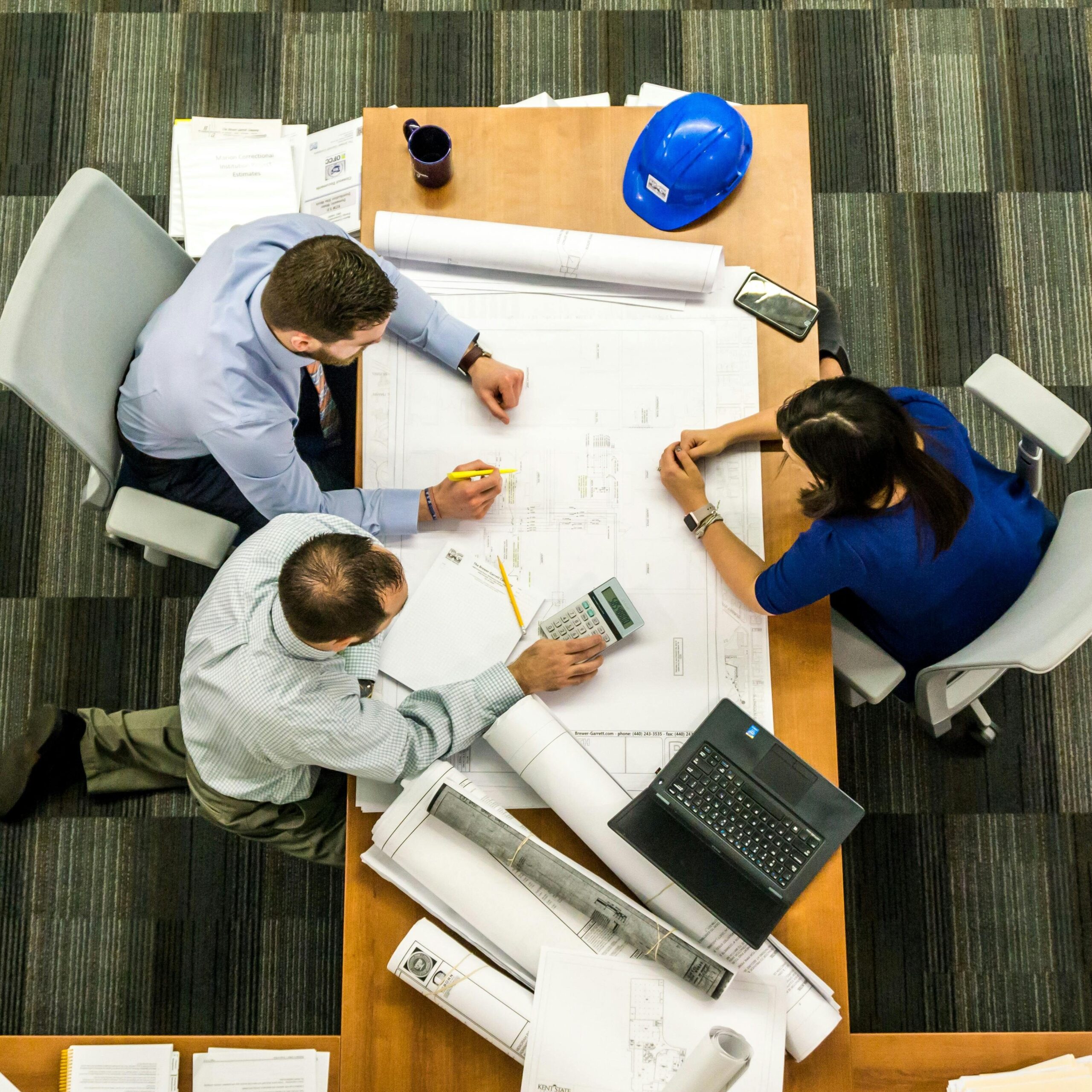 Top view of a team working on construction plans in an office setting.