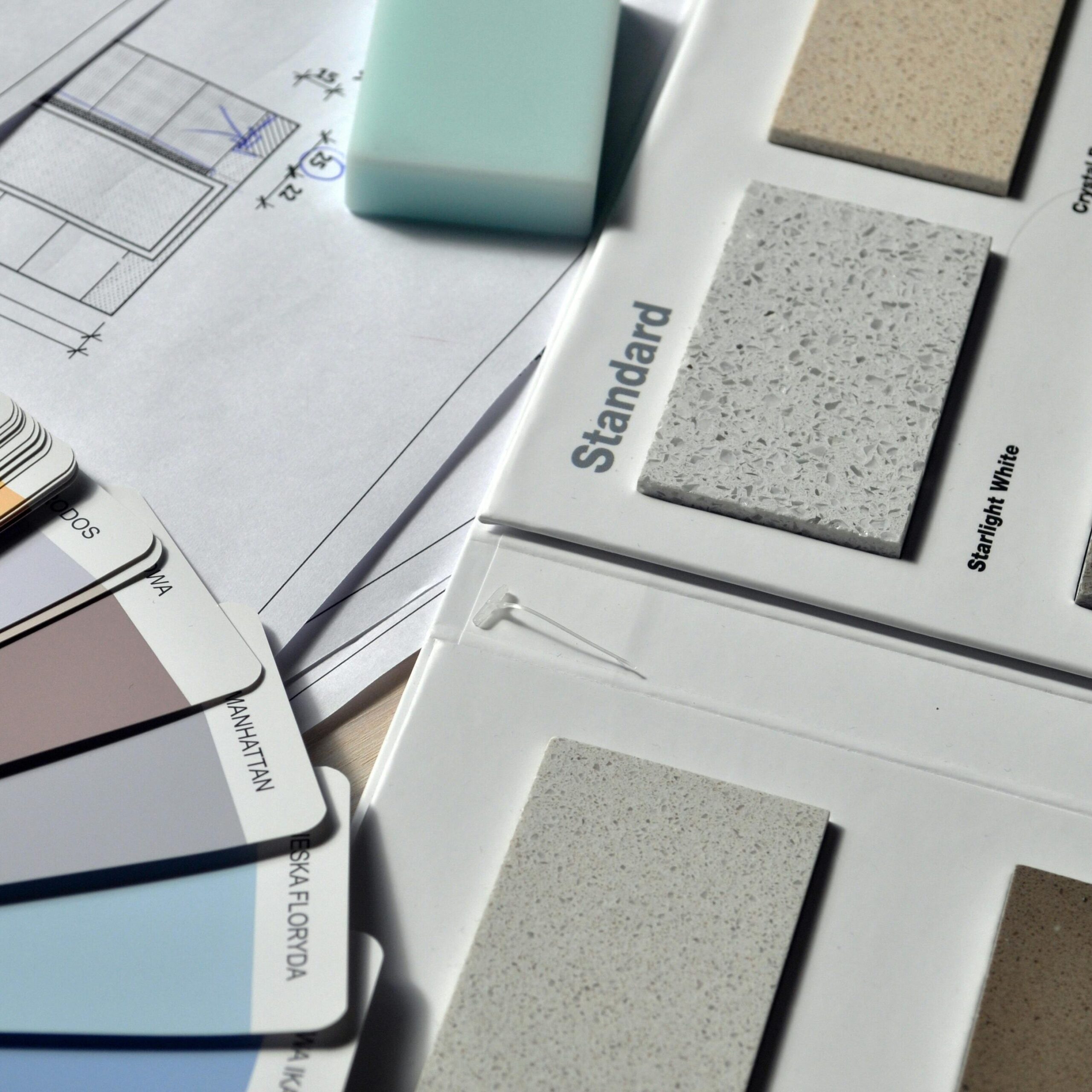 Color palette and material samples for interior renovation projects on a blueprint.